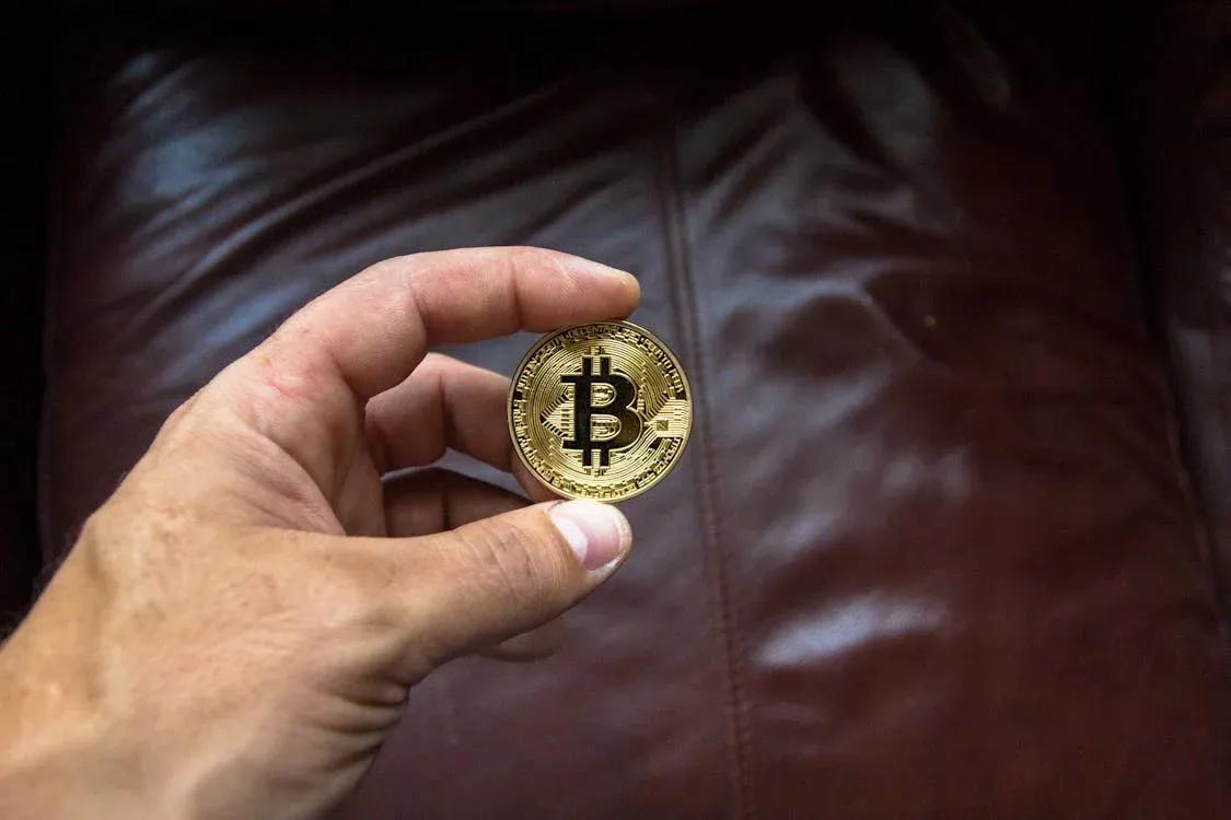 A photo of a hand holding a Bitcoin