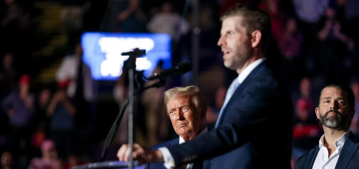 Eric Trump speaking on stage with his father and brother behind him