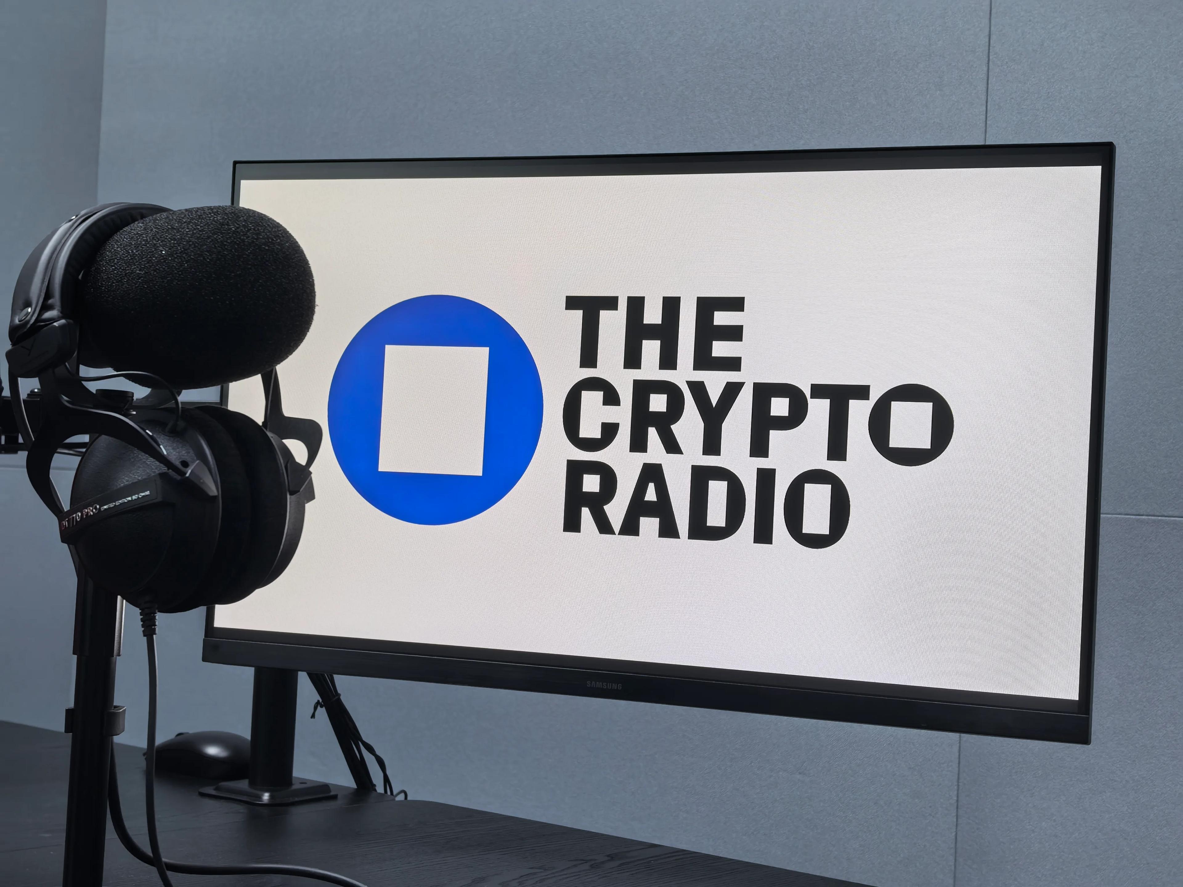 A microphone in a studio next to a screen bearing The Crypto Radio logo