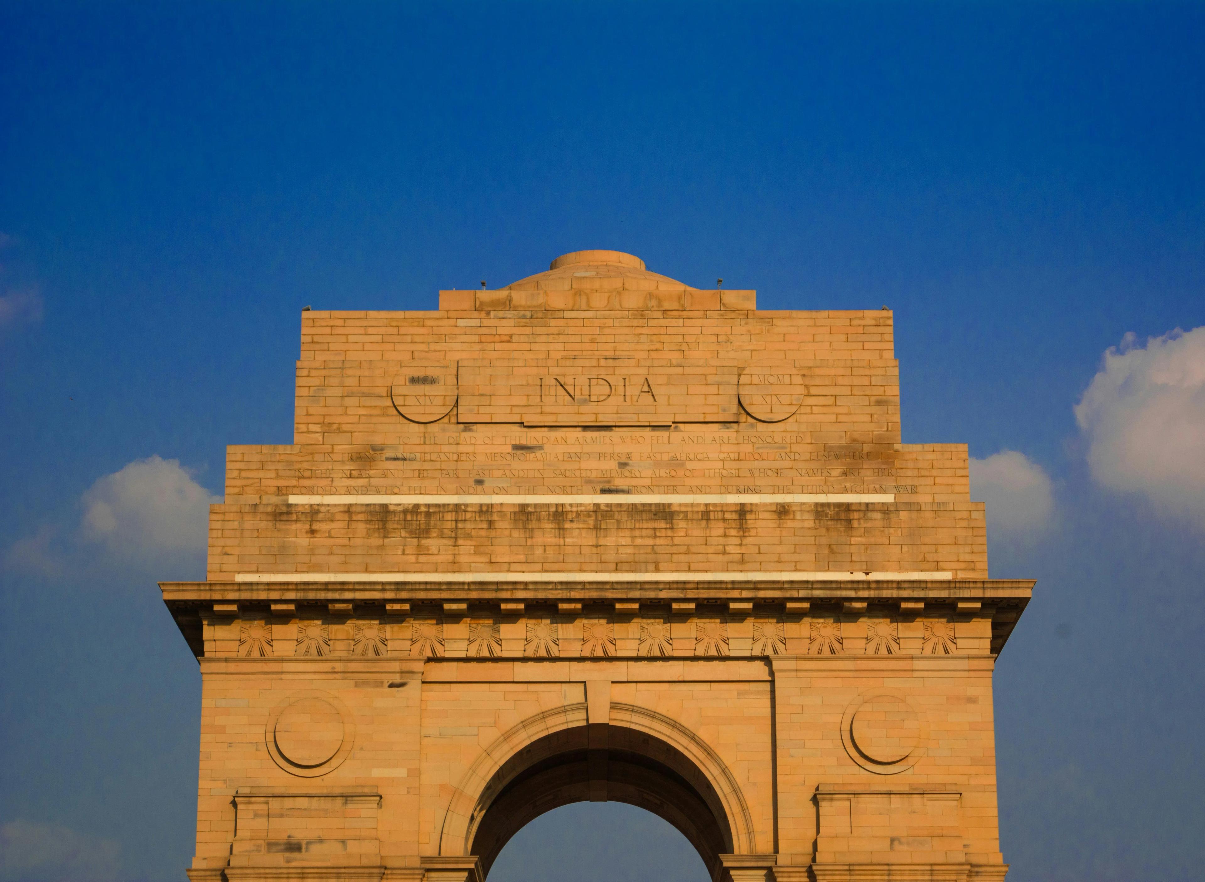 An orange brick building with the word India engraved on it against a blue sky