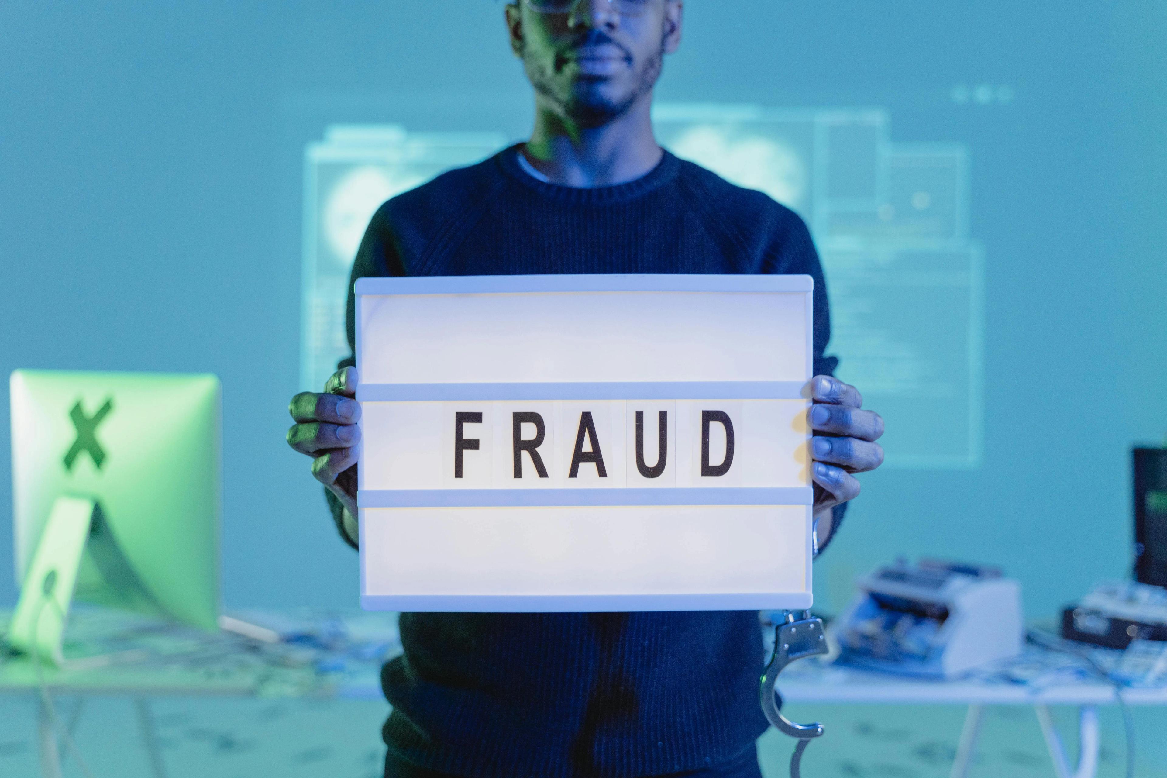 Man holding lightbox with the word fraud on it